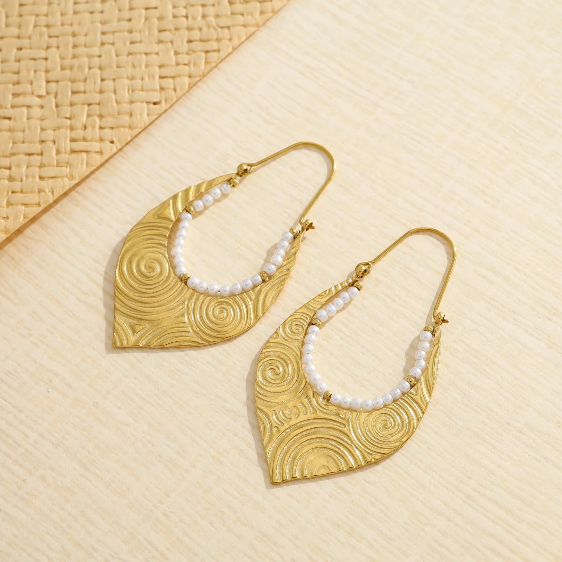 Boucles d'oreilles dorées pendant goutte inversé spirale entouré de perles blanches